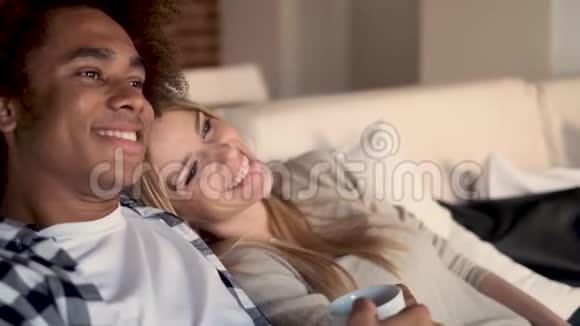 幸福的年轻夫妇坐在家里的沙发上一起看电视视频的预览图