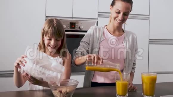 漂亮的年轻母亲和女儿在家厨房准备早餐视频的预览图