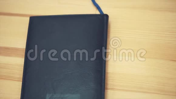 年轻的商务女性手打开一个黑色的笔记本写一幅铅笔画记事本在桌子上视频的预览图