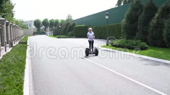 一位骑着电动个人运输车从摄像机前经过的女人视频的预览图