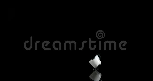 一杯牛奶在黑色背景上弹跳和飞溅慢动作视频的预览图