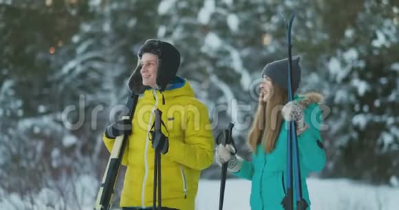 一对活跃的年轻夫妇在白雪皑皑的冬林中享受滑雪的完整肖像集中在微笑的女人面前视频的预览图