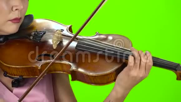 用棕色小提琴弹奏琴弦的女孩快关门绿色屏幕视频的预览图