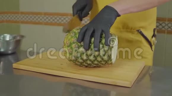 男厨师正在厨房里剥一个菠萝特写镜头视频的预览图