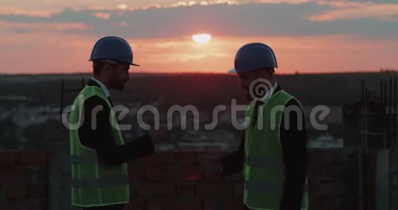 建筑工地的两名工人在楼顶玩手视频的预览图