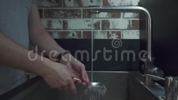 一个男人在厨房里用清洁海绵洗一个勺子视频的预览图