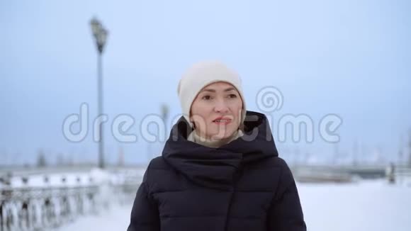一个女人沿着一条下雪的街道走冬天阴天一个女人穿过城市视频的预览图