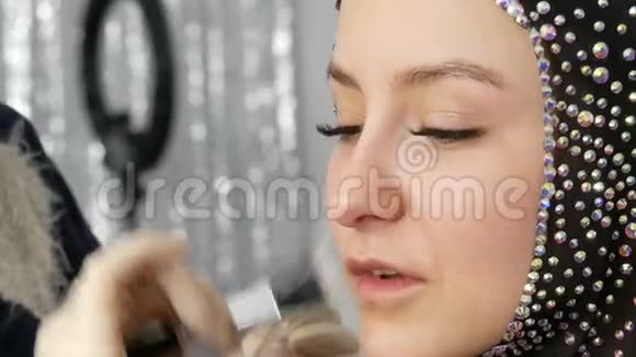 化妆底座应用于模特特写的面部年轻女孩模特在工作室里有一双漂亮的棕色眼睛视频的预览图