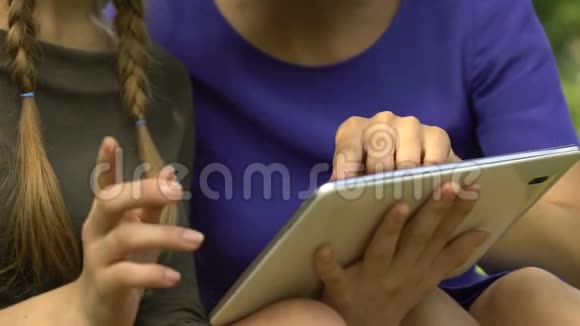女儿在现代平板电脑上显示母亲的移动应用程序在网上购物视频的预览图