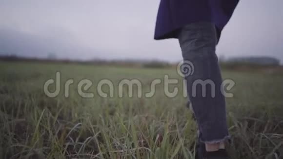 一个穿着运动鞋和外套的女人在潮湿的草地上视频的预览图