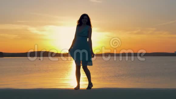 在日落的背景下美丽的女人跳舞和拍照的剪影视频的预览图