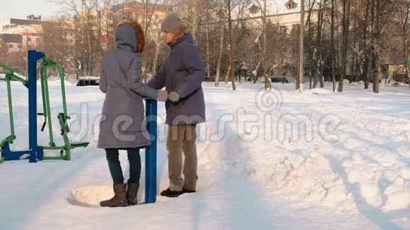 穿着蓝色夹克的男人和女人在冬季公园里从事模拟器和谈话侧视视频的预览图