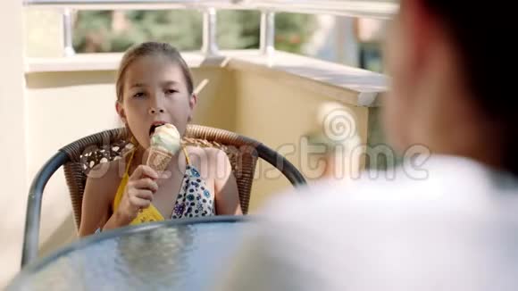 一个女人带着一个小女儿坐在阳台上的桌子上吃冰淇淋视频的预览图
