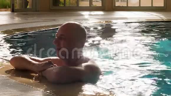 在豪华酒店边缘附近的游泳池里放松身心的成人肖像画视频的预览图
