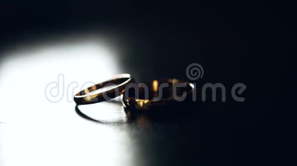 两个结婚戒指躺在桌子上被一束明亮的光照亮特写视频的预览图