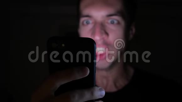 愤怒的人在晚上使用智能手机手里拿着智能手机的愤怒的吼叫男人视频的预览图