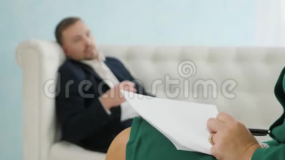 年轻的商人坐在沙发上和他的治疗师在治疗会议上交谈视频的预览图