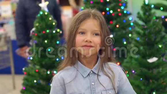 超市里的一个小女孩在圣诞树的背景上玩耍视频的预览图