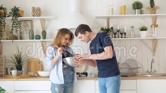 金发女人把食物倒在碗里男人在厨房品尝视频的预览图