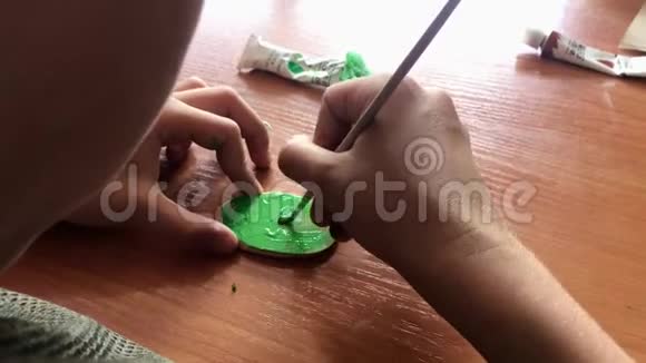一个孩子画一个绿色的小木刻的特写镜头手工艺活动视频的预览图