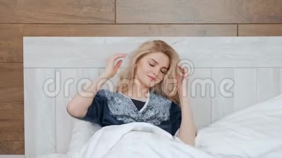 年轻漂亮的女人穿着浴袍躺在床上躺在白色的枕头上视频的预览图