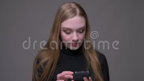 年轻迷人的黑发女性在手机上浏览开心地笑着看着镜头特写照片视频的预览图