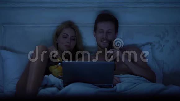 甜蜜的夫妻在笔记本电脑上看节目微笑和交谈幸福视频的预览图