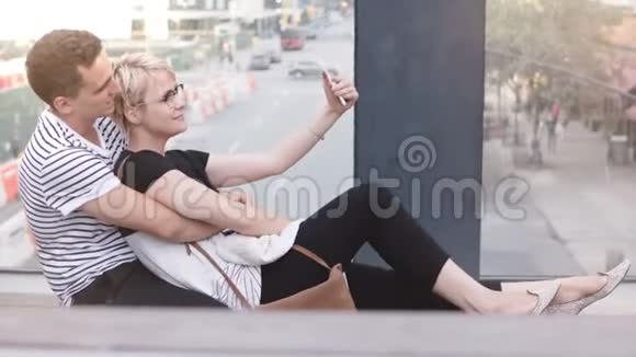 快乐的多民族浪漫夫妇坐在纽约街桥上拍智能手机自拍开心的微笑视频的预览图