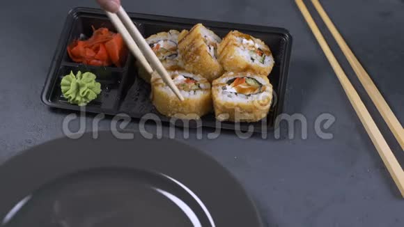 手拿筷子拿寿司寿司卷在深色盘子上是吃零食的时候视频的预览图