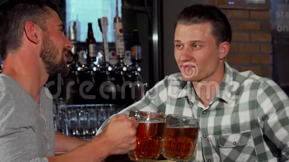 快乐的男性朋友在酒吧边喝啤酒边看比赛视频的预览图