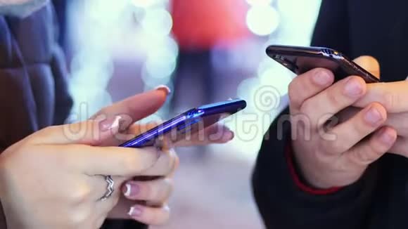 在下雪的傍晚男人和女人的亲密手用手机和朋友聊天用灯和装饰品视频的预览图