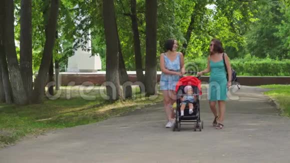 妈妈和女朋友把一个孩子卷进婴儿车里视频的预览图