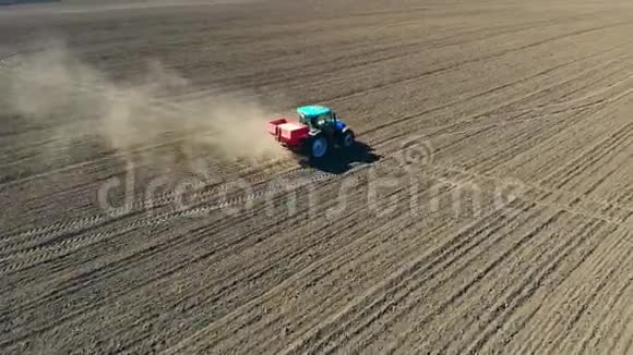 农用拖拉机在大轮子上的空中视野跨越肥沃的农田传播矿物肥料视频的预览图