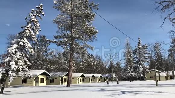 阳光明媚的一天一排黄色的夏季小屋被雪覆盖视频的预览图