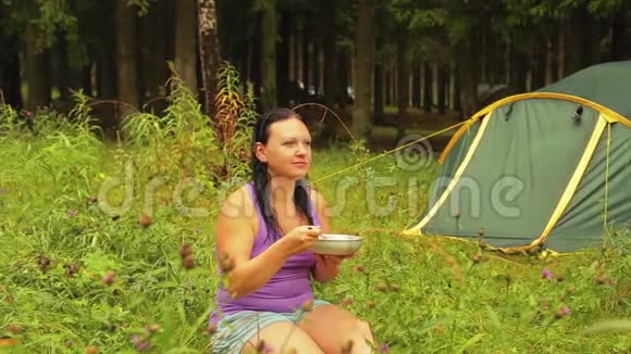 微笑的女人坐在帐篷附近吃水果沙拉视频的预览图
