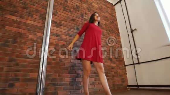 穿红色衣服的女孩训练钢管舞在杆子上跳跃视频的预览图