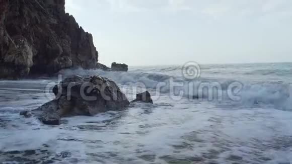 平静的海浪拍打着洞穴附近的岩石视频的预览图