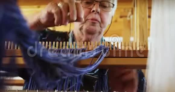 老白种人高级妇女在工作中准备和坐在手中织布机的低角度视角视频的预览图