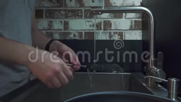 一个男人在厨房里用海绵洗了一铲子视频的预览图