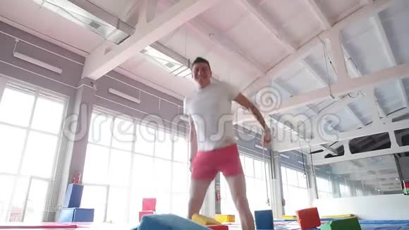 健身娱乐理念一个年轻健康的快乐男人在蹦床上跳跃视频的预览图