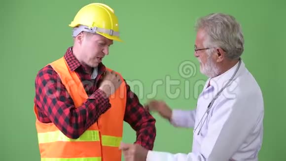 高级胡子男医生咨询建筑工人男病人视频的预览图