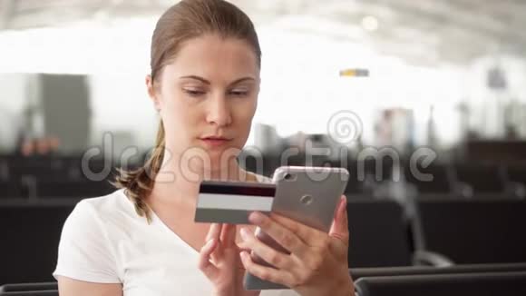机场女性在等待航班起飞时使用智能手机信用卡在线购物视频的预览图