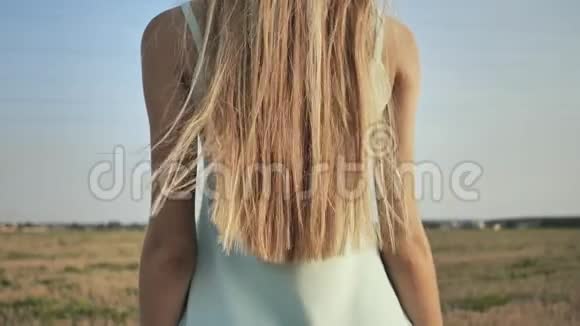 一个年轻的金发女孩站在背后展示她的长发视频的预览图