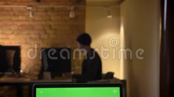 通过摄像头拍摄的特写镜头从员工的视线转移到笔记本电脑桌面上有绿色屏幕视频的预览图
