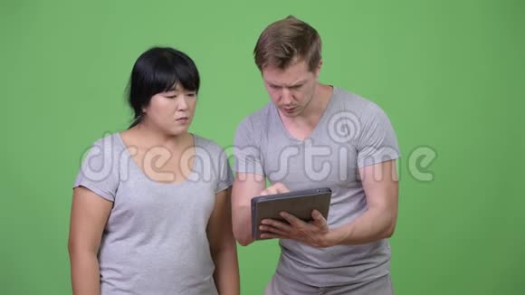年轻的多民族夫妇使用数字平板电脑一起得到坏消息视频的预览图