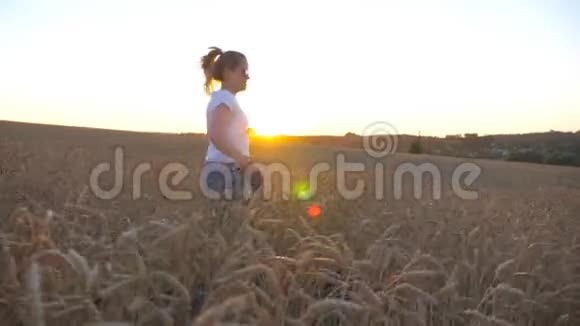年轻女孩手里拿着金色麦秆用皮带在草地上慢跑视频的预览图