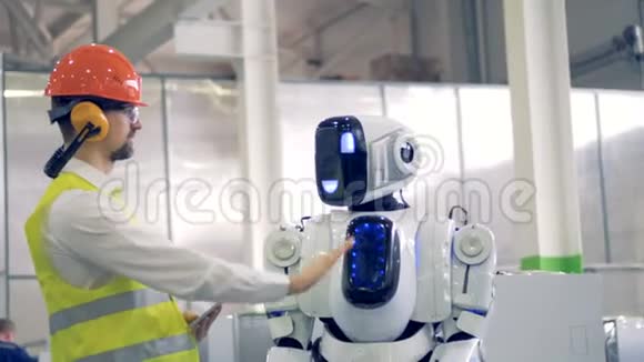 人类工厂的工人和一个机器人在工厂设施里给对方一个击掌视频的预览图