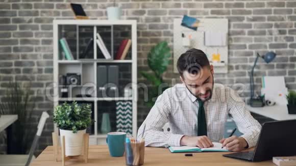 年轻人在笔记本上写字用笔记本电脑坐在办公桌前视频的预览图