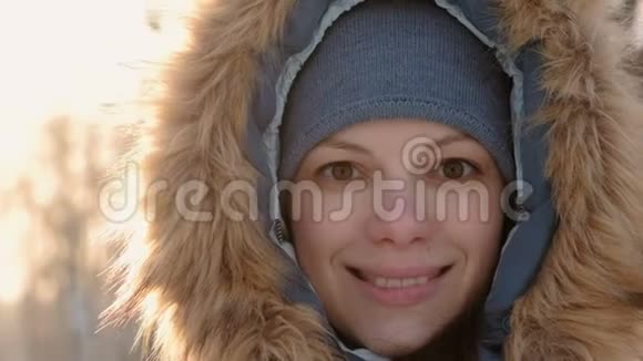 在冬天的公园里穿着毛皮罩的特写女人脸在镜头里看着微笑着就在录像里视频的预览图