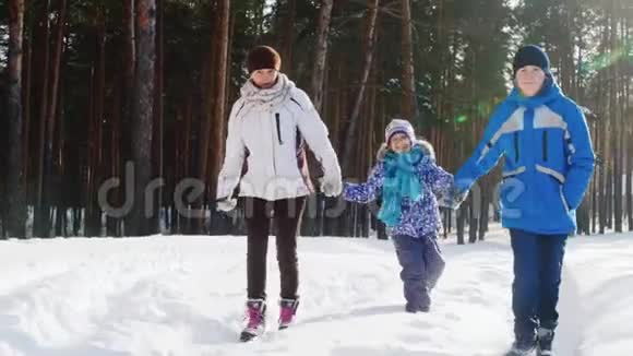 有两个孩子的母亲正沿着白雪覆盖的森林散步视频的预览图
